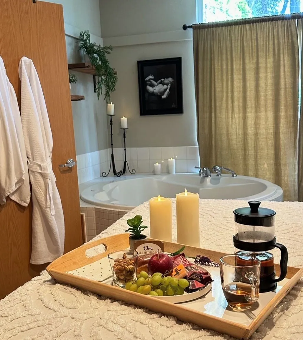 A tray of fruit, tea and candles on a bed beside a birth tub