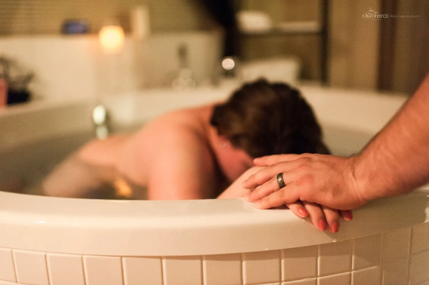 A mother laboring in a birth tub at The Birthing Inn while her partner holds her hand